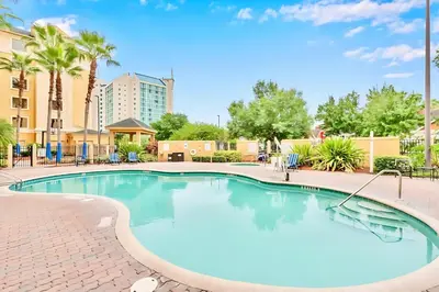a swimming pool at a resort with chairs and trees at Family-Friendly 1BR Apartment close to Disney World in Orlando