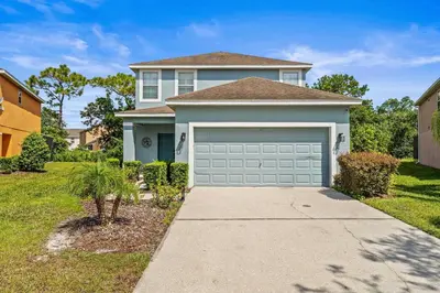 a house with a garage door in a yard at Paradise Falls Stay for 13 in Kissimmee