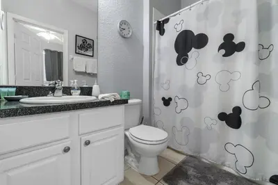 a bathroom with a toilet and a sink and a shower curtain at Disney Dream in Orlando
