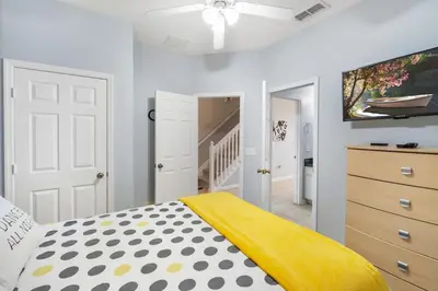 a bedroom with a bed with a yellow blanket on it at Disney Dream in Orlando