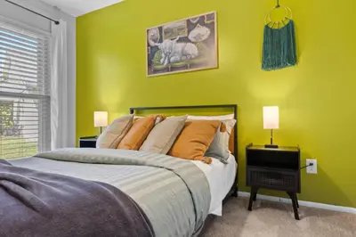 a bedroom with a bed and a yellow wall at Red Jordan Boho Style Vacation Home in Orlando