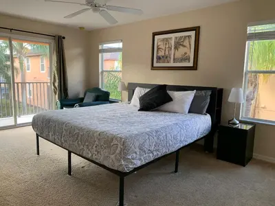 a bedroom with a bed with a blue comforter at Spacious 4 BR Townhouse with 2 King Size Master Bedrooms, 3 miles to Disney, Free WiFi and Free Parking in Orlando