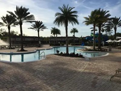 a pool with palm trees in a resort at Spacious 4 BR Townhouse with 2 King Size Master Bedrooms, 3 miles to Disney, Free WiFi and Free Parking in Orlando