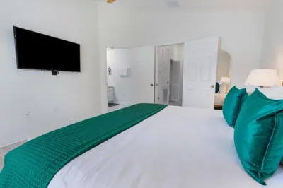 a bedroom with a large white bed with green pillows at Windsor Hills Family-Friendly 3BR Pool Townhome in Orlando