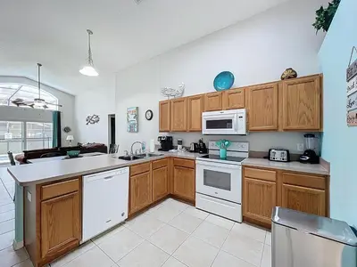 a kitchen with white appliances and wooden cabinets at Family Fun Tropical Home in Kissimmee