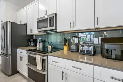 a kitchen with white cabinets and stainless steel appliances at Casa 4Q Storey Lake c/ Piscina e Quartos Disney in Kissimmee