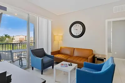 a living room with a couch and chairs and a clock at Apartamento 3Q Vista Cay Perto dos Parques in Orlando