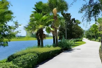 a walking path next to a lake with palm trees at Apartamento 3Q Vista Cay Perto dos Parques in Orlando