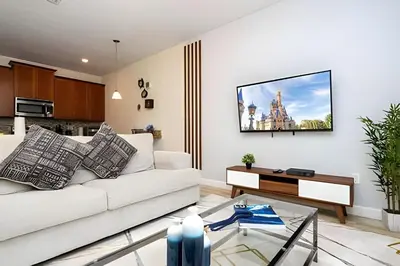 a living room with a couch and a tv on a wall at Casa 4Q c/ Piscina e Temas Mickey & Harry Potter in Kissimmee