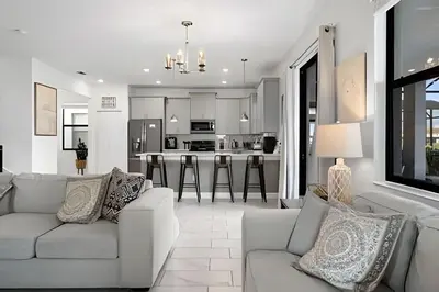 a living room with a couch and a kitchen at Villa 6Q Luxo c/ Piscina, Spa e Perto da Disney in Kissimmee