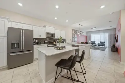 a kitchen with white cabinets and a kitchen island with chairs at Cozy 2 Bedrooms At Storey Lake in Kissimmee