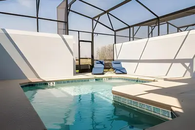 a swimming pool with two chairs in a building at Casa 4Q c/ Piscina e Quartos Temáticos in Kissimmee