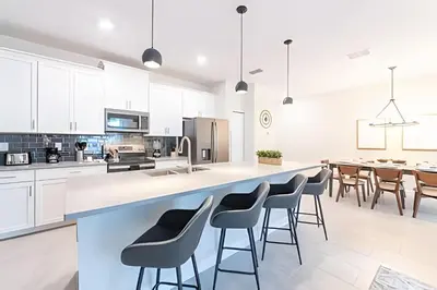 an open kitchen with white cabinets and bar stools at Casa 4Q Storey Lake c/ Piscina e Mickey in Kissimmee