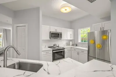 a kitchen with white cabinets and a stainless steel refrigerator at Sleek & Stylish Stay Mins to Magic MP68 in Orlando
