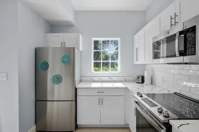 a kitchen with a stainless steel refrigerator and white cabinets at Serene Disney Getaway Designer Style MP61 in Orlando