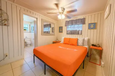 a bedroom with an orange bed and a bathroom at Cottage-pvt Lake & Pool Access Near Disney Wporch in Clermont