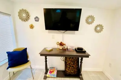 a room with a table and a tv on the wall at Lilac Loft- Lake, Pool, Pickle Ball, Disney, Fun! in Clermont