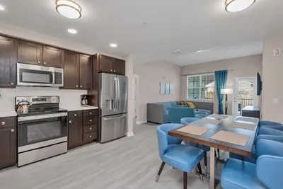 a kitchen and living room with a table and blue chairs at WOW New Upscale Penthouse in Orlando
