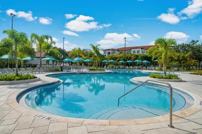 a swimming pool at a resort with blue umbrellas at Penthouse Corner at Vista Cay in Orlando