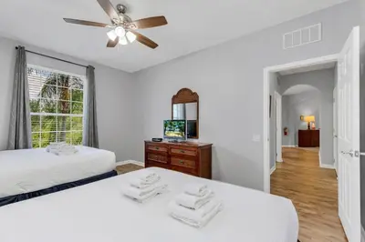 a white bedroom with two beds and a ceiling fan at Conservation View Updated WOW in Orlando