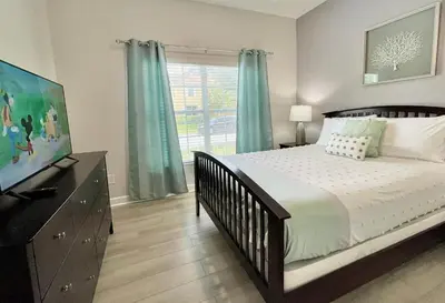 a bedroom with a bed and a television and a window at Cheerful 5 Bdr Sunny Pool in Kissimmee