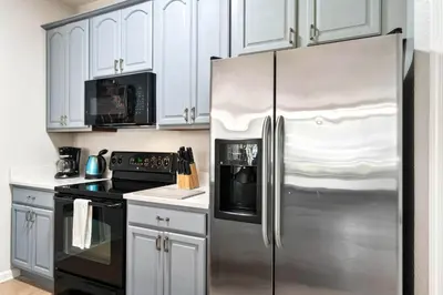 a kitchen with white cabinets and a stainless steel refrigerator at Vista Cay Remodeled WOW in Orlando