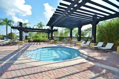 a swimming pool in a patio with chairs and an umbrella at Vista Cay Remodeled WOW in Orlando