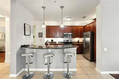 a kitchen with wooden cabinets and a island with bar stools at Huge Luxury Ground Floor 103 in Orlando