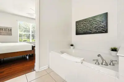 a white bathroom with a tub and a bed at Huge Luxury Ground Floor 103 in Orlando