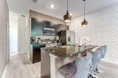 a kitchen with a counter and blue bar chairs at Luxury Town House Near Disney in Kissimmee