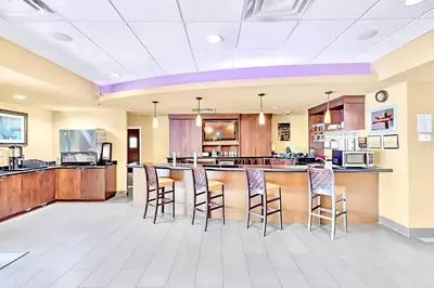 a large kitchen with a bar with stools at Stylish King Apt w Arcade Game & BBQ Near Disney in Orlando