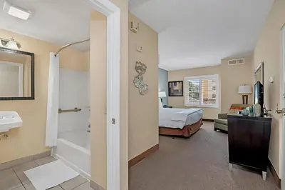 a hotel room with a bed and a bathroom at Stylish King Apt w Arcade Game & BBQ Near Disney in Orlando