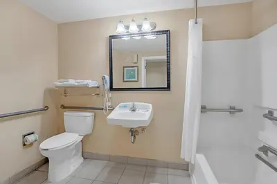 a bathroom with a toilet and a sink and a mirror at Stylish King Apt w Arcade Game & BBQ Near Disney in Orlando