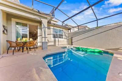 a house with a swimming pool and a patio with a table at Gorgeous 5Bd w Pool & Lazy River at Storey Lake 4989 in Kissimmee