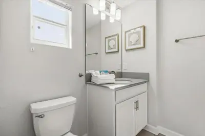 a white bathroom with a toilet and a mirror at 5 Bedrooms 4 Bathrooms Storey Lake 4984Wa in Kissimmee