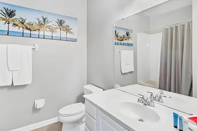 a bathroom with a sink and a toilet and a mirror at Vista Cay: 4Q c/ Varanda e Mesa de Pebolim in Orlando