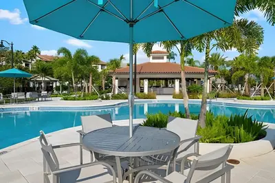 a table and chairs with an umbrella next to a pool at Vista Cay: 4Q c/ Varanda e Mesa de Pebolim in Orlando
