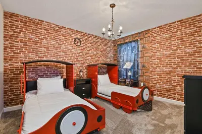 a bedroom with a bed and a childs bed in a brick wall at 9 MI to Disney w Pool Cinema & FREE Waterpark in Kissimmee