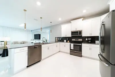 a kitchen with white cabinets and stainless steel appliances at Themed 9BR Retreat Pool & Soccer Fun in Kissimmee