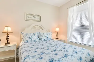 a white bedroom with a bed with blue flowers at Condo 3Q Windsor Hills — Perto da Disney in Orlando