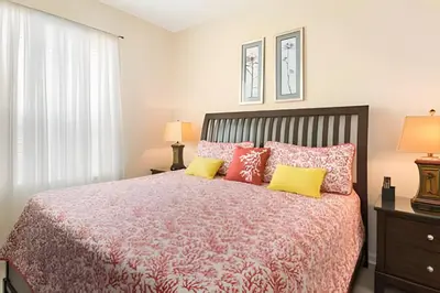 a bedroom with a bed with red and yellow pillows at Condo 3Q Windsor Hills — Perto da Disney in Orlando