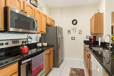 a kitchen with wooden cabinets and a stainless steel refrigerator at Condo 3Q Windsor Hills — Perto da Disney in Orlando