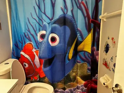 a bathroom with a toilet with a fish shower curtain at Disney Magic Condo 1st Flr 3BR Disney-Themed Pool in Kissimmee