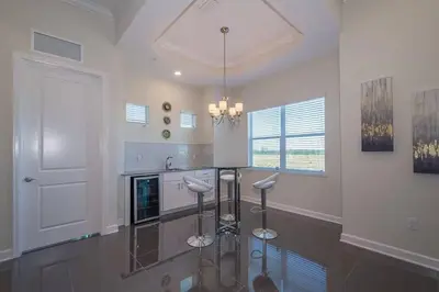 a kitchen with a glass counter and stools at Spacious Villa w Pool Slides and Lush Nature Views in Kissimmee