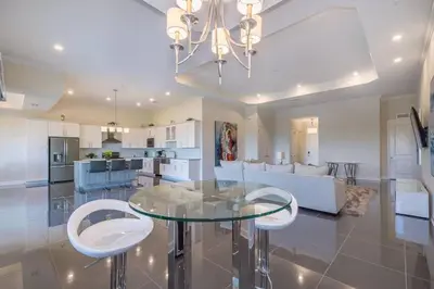 a kitchen and living room with a glass table and chairs at Spacious Villa w Pool Slides and Lush Nature Views in Kissimmee