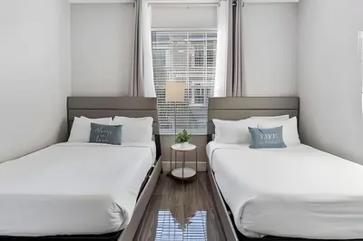 two beds in a room with two windows at Townhouse Moderna 4Q — Perto da Universal in Orlando