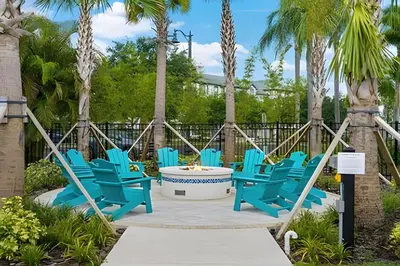 a group of blue chairs sitting on a patio with palm trees at Apartamento 3Q Vista Cay c/ Varanda e Jogos in Orlando