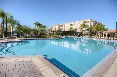 a large swimming pool at a resort with palm trees at Apartamento 3Q Vista Cay c/ Varanda e Jogos in Orlando