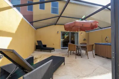a patio with a table and chairs and an umbrella at Cozy 2 bedrooms with Hot tube in Kissimmee