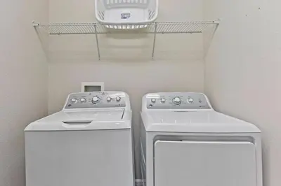 a laundry room with two washing machines and a shelf at Magical Memories Villa 10bd Near Disney in Orlando